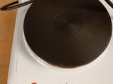 a white stove top with a black burner on it