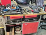 un établi sur lequel sont posés des outils, avec une voiture en arrière-plan