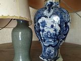 un vase bleu et blanc posé à côté d'une lampe sur une table