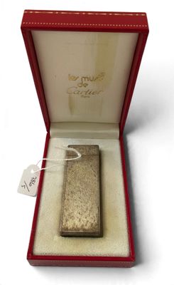 un briquet argenté dans une boîte rouge posée sur une surface blanche