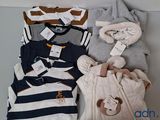 une pile de vêtements de bébé posée sur une étagère à côté d'une peluche