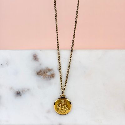 un collier en or orné d'une pièce, posé sur une surface en marbre