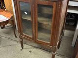 a small cabinet with a glass door in the middle of a room