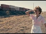 a woman standing on the side of the road talking on a cell phone