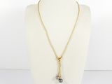 a gold necklace with two pearls on a mannequin neck