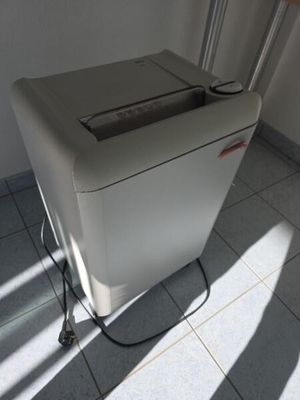 une déchiqueteuse à papier blanche posée sur un sol carrelé