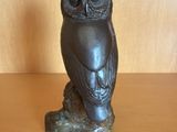 statue d'un hibou perché sur une branche, posée sur une table en bois