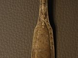 a close up of a silver spoon on a leather surface