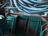 tables and chairs in a restaurant with a painting on the wall