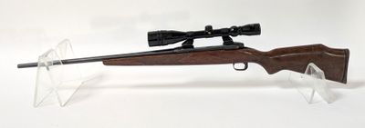 le fusil repose sur un support transparent équipé d'une lunette de visée
