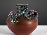 un vase marron avec des fleurs violettes posé sur une table