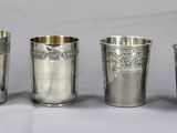 Quatre coupes en argent ornées de motifs sont alignées sur une table