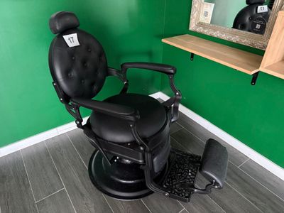 une photo d'un fauteuil de coiffeur noir dans une salle verte