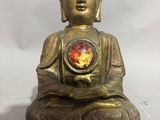 statue d'un Bouddha assis sur un rocher, tenant une pierre rouge dans la main