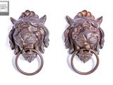 pair of bronze lion head door knockets on a white background