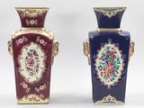 Deux vases ornés de motifs floraux sont posés côte à côte sur une surface blanche