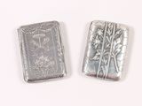 two silver metal lighters sitting next to each other on a white surface