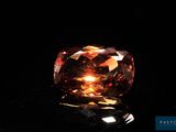 a close up view of a fancy orange diamond on a black surface