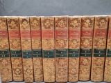 six old books are lined up in a row on a gray surface