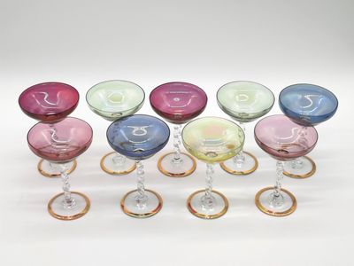 several different colored wine glasses are lined up on a white surface