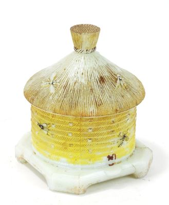 un vase jaune et blanc muni d'un couvercle, posé sur un socle