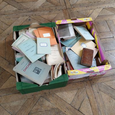 a green box filled with books and papers on a wooden floor