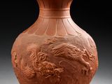 un vase orange orné d'un dragon, posé sur une table