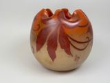 un petit vase avec un motif sur une surface blanche
