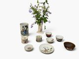 un vase rempli de fleurs posé à côté d'un tas de bols