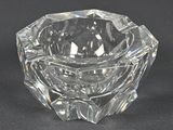 un bougeoir en verre transparent posé sur une surface noire