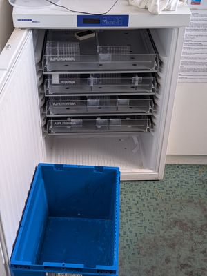 une photo d'un réfrigérateur avec un bac bleu à côté