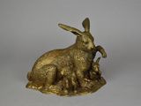 une image représentant une figurine de lapin en or posée sur une surface blanche