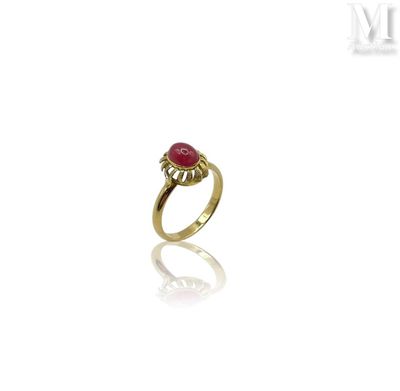 a close up of a gold ring with a red stone