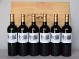 six bouteilles de vin rouge sont alignées devant une caisse en bois