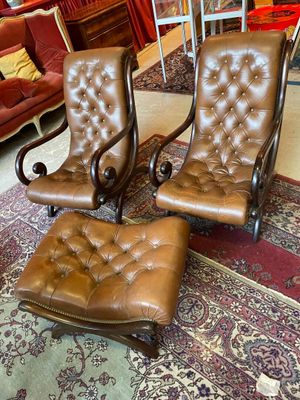 deux fauteuils en cuir marron et un pouf marron dans un salon