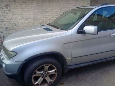 a silver bmw suv parked in front of a brick wall