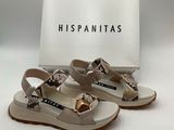 Les chaussures sont de couleur beige et blanche, avec un nœud doré sur le bout.