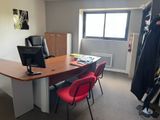 un bureau avec un écran d'ordinateur et des chaises rouges dans une pièce