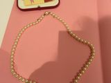 a pearl necklace on a pink table next to a pink book