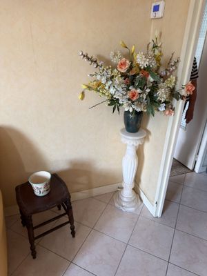 a vase of flowers on a pedestal in the corner of a room
