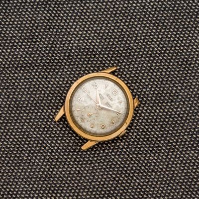 une montre en or posée sur un morceau de tissu