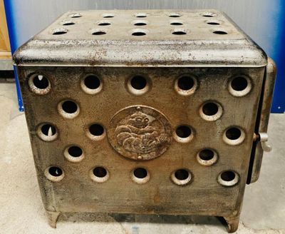 une boîte métallique percée de trous, posée par terre