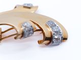a gold brooch with diamonds on it on a white surface