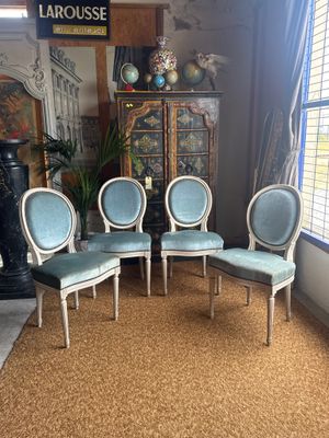 four chairs in a room with a rug and a lamp