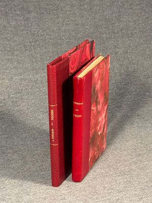 two red books sitting next to each other on a gray surface