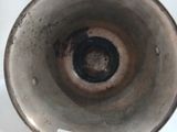 un gros plan d'un vase argenté posé sur une surface blanche
