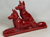 une statue rouge représentant deux chiens assis sur une table