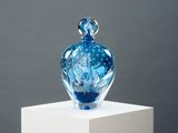 a blue glass vase sitting on top of a white pedestal