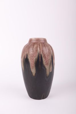 un vase noir et marron posé sur une surface blanche