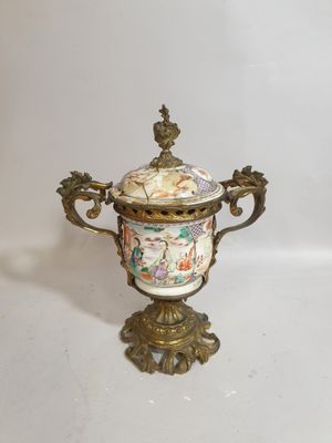 un vase muni d'un couvercle, posé sur un socle, sur une surface blanche